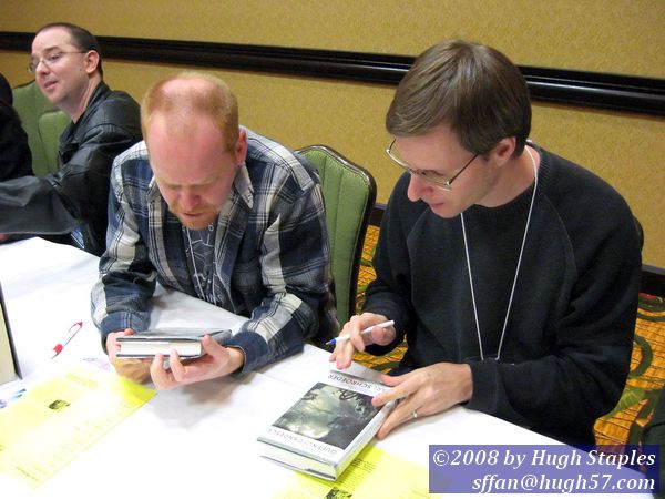 Karl Schroeder prepares to sign his Virga Books while Matt Jarpe admiires the Stephan Martineire cover art