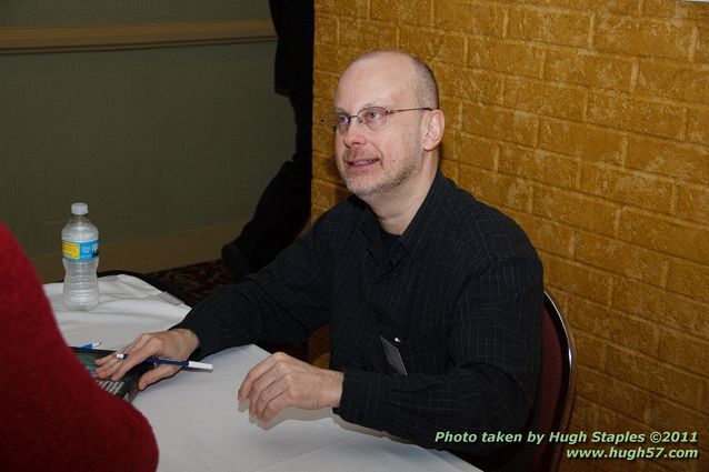 Guest of Honor Robert J. Sawyer signs books at the Autograph Table