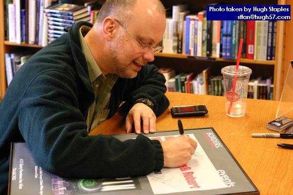 Rob signs in-store poster for the store manager
